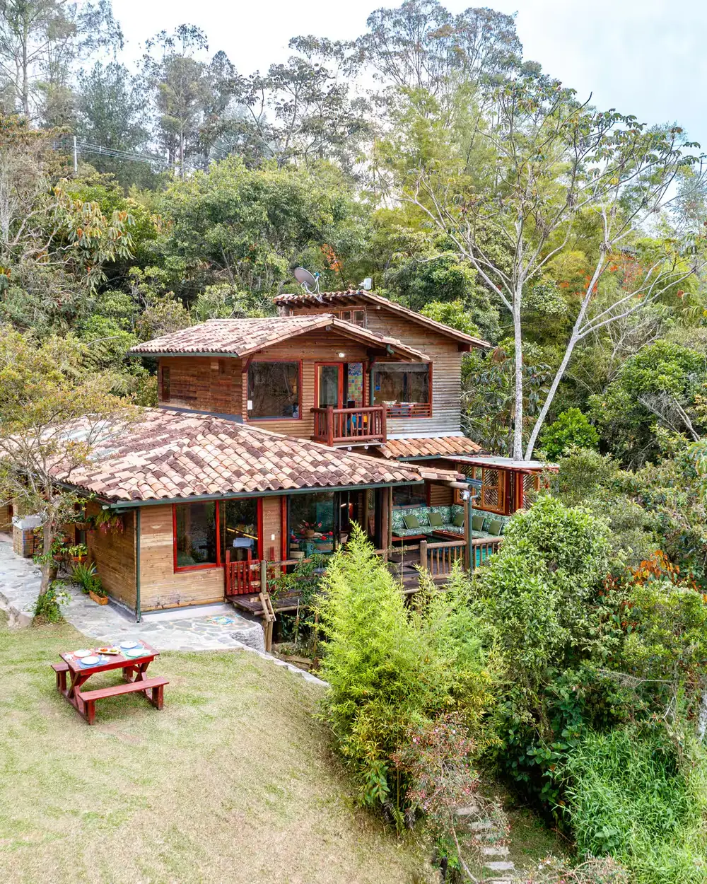 A country farmhouse with a tiled roof, among trees and garden.