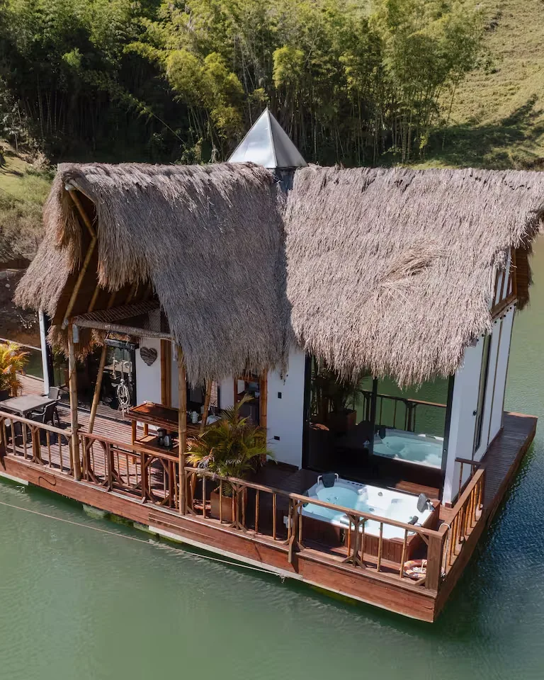 A thatched-roof cabin built on a floating platform on the reservoir, with a hot tub on the terrace.