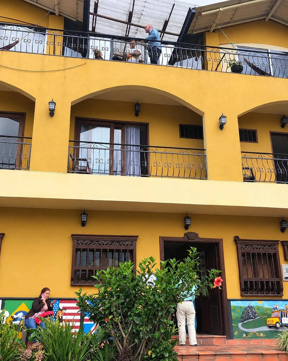 The yellow façade of a hostel in Guatapé, with arches, iron balconies and painted zócalos along the base.