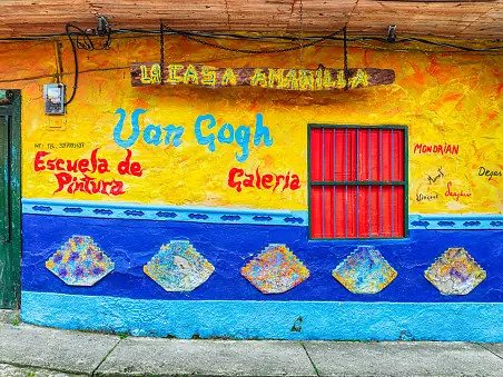 Fachada de La Casa Amarilla, escuela de pintura y galería, con zócalos azules.
