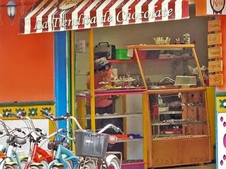 Una tienda de chocolate y dulces con toldo de rayas y bicicletas en la puerta.