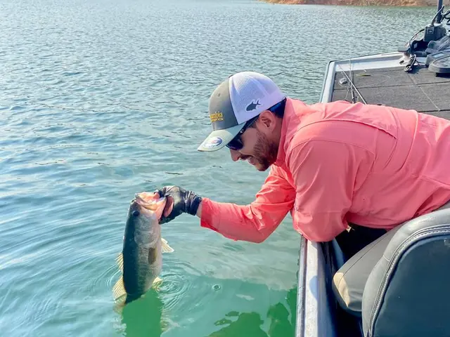 Un pescador levantando su captura desde un bote en el embalse.