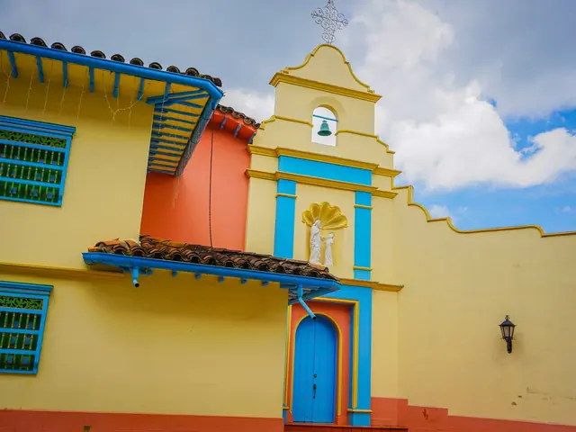 La fachada amarilla de la Capilla Hermanas de Santa Ana, con su espadaña, la campana y la puerta azul.