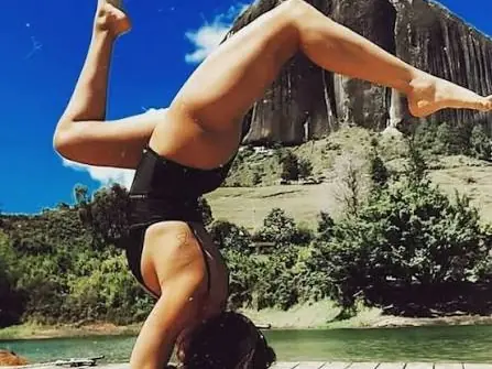 Una persona haciendo una postura de yoga invertida frente al Peñón.