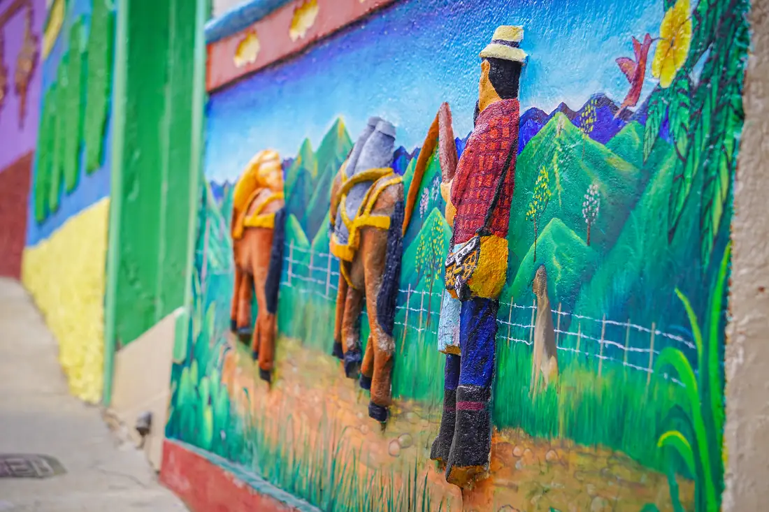A relief zócalo with a muleteer and his loaded mules among green mountains.