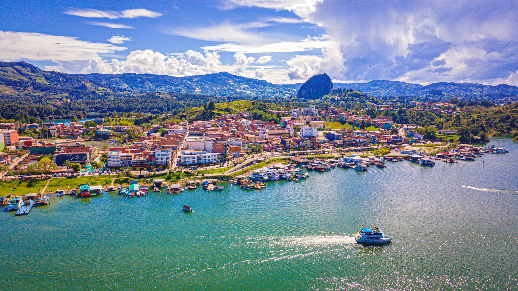 The town of Guatapé on the reservoir, with the mountains and El Peñón de Guatapé —La Piedra del Peñol— in the background.
