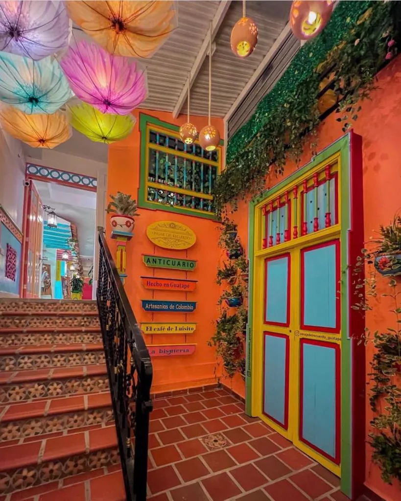 La entrada del Anticuario Pasaje del Recuerdo, con sombrillas de colores en el techo, una escalera de ladrillo y una puerta azul.