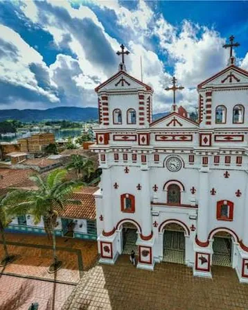 La Iglesia de Nuestra Señora del Carmen, blanca con molduras rojas, sobre el parque principal de Guatapé.
