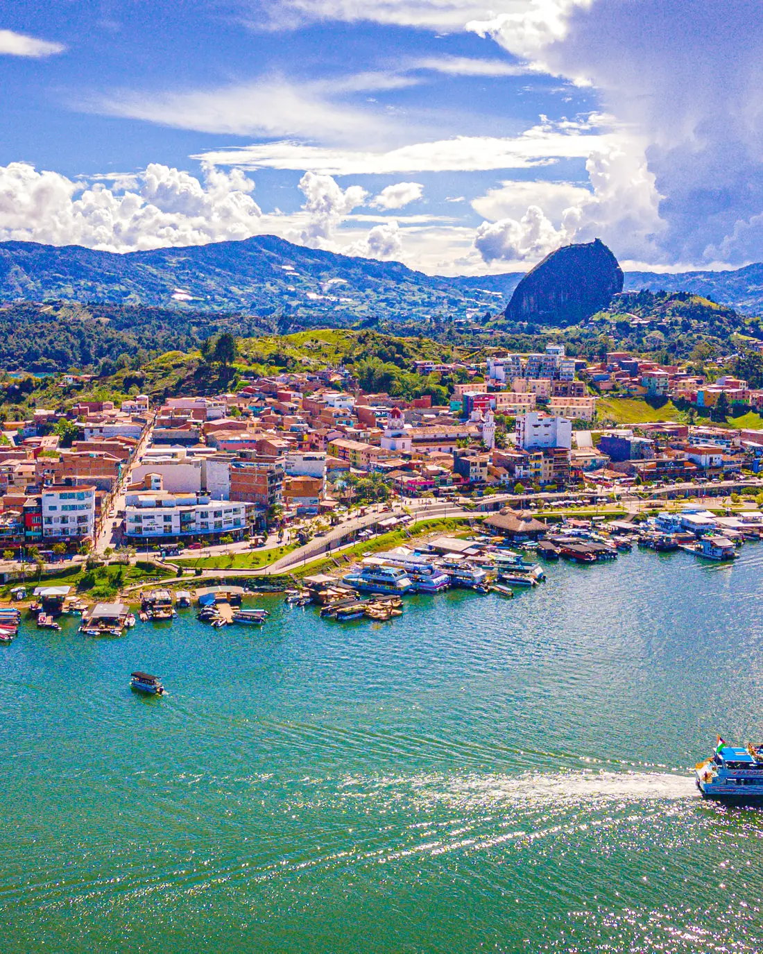 El Malecón San Juan del Puerto y el pueblo de Guatapé vistos desde el embalse, con el Peñón al fondo.